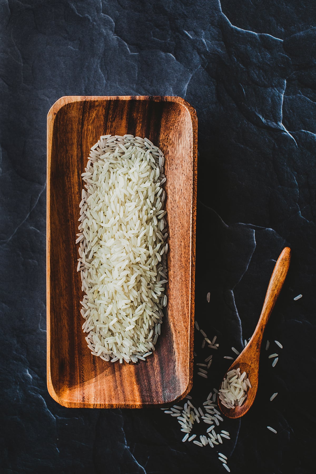 Thai jasmine rice in  wooden bowl with a spoon on the side.