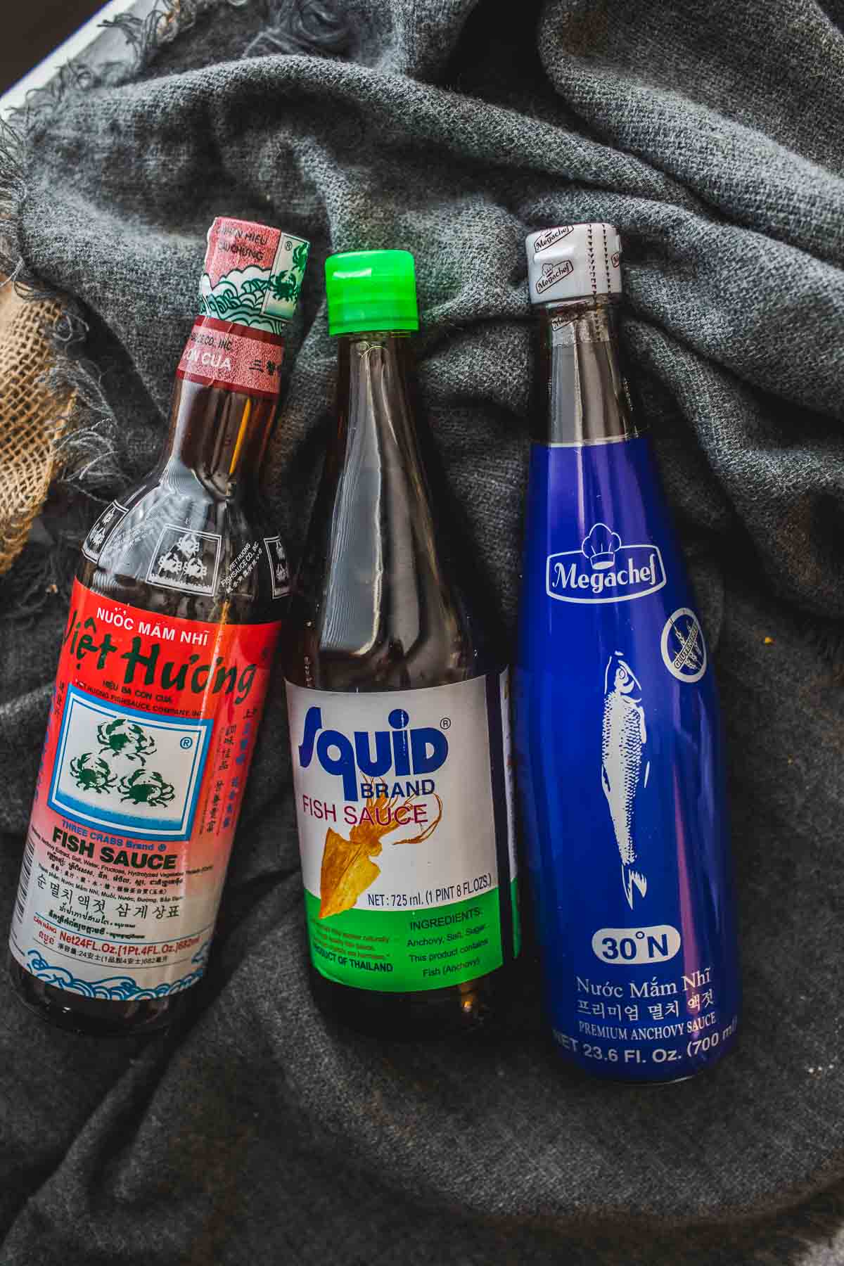 3 bottle of different brands of fish sauce on a cloth.