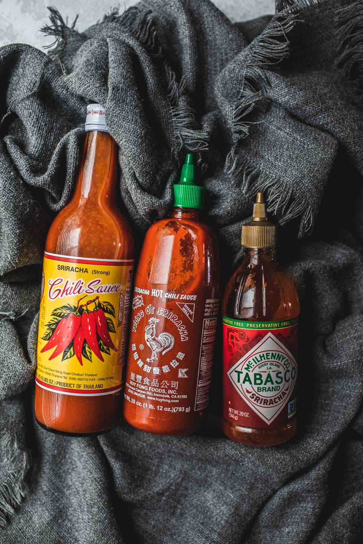 3 types of Sriracha sauce on a table.