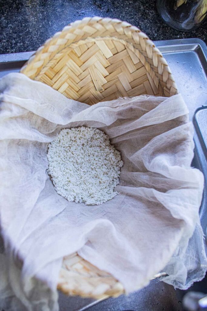 Sticky rice in a bamboo basket with cheesecloth.