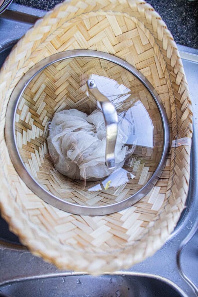 Sticky rice in a bamboo basket with cheesecloth and lid.