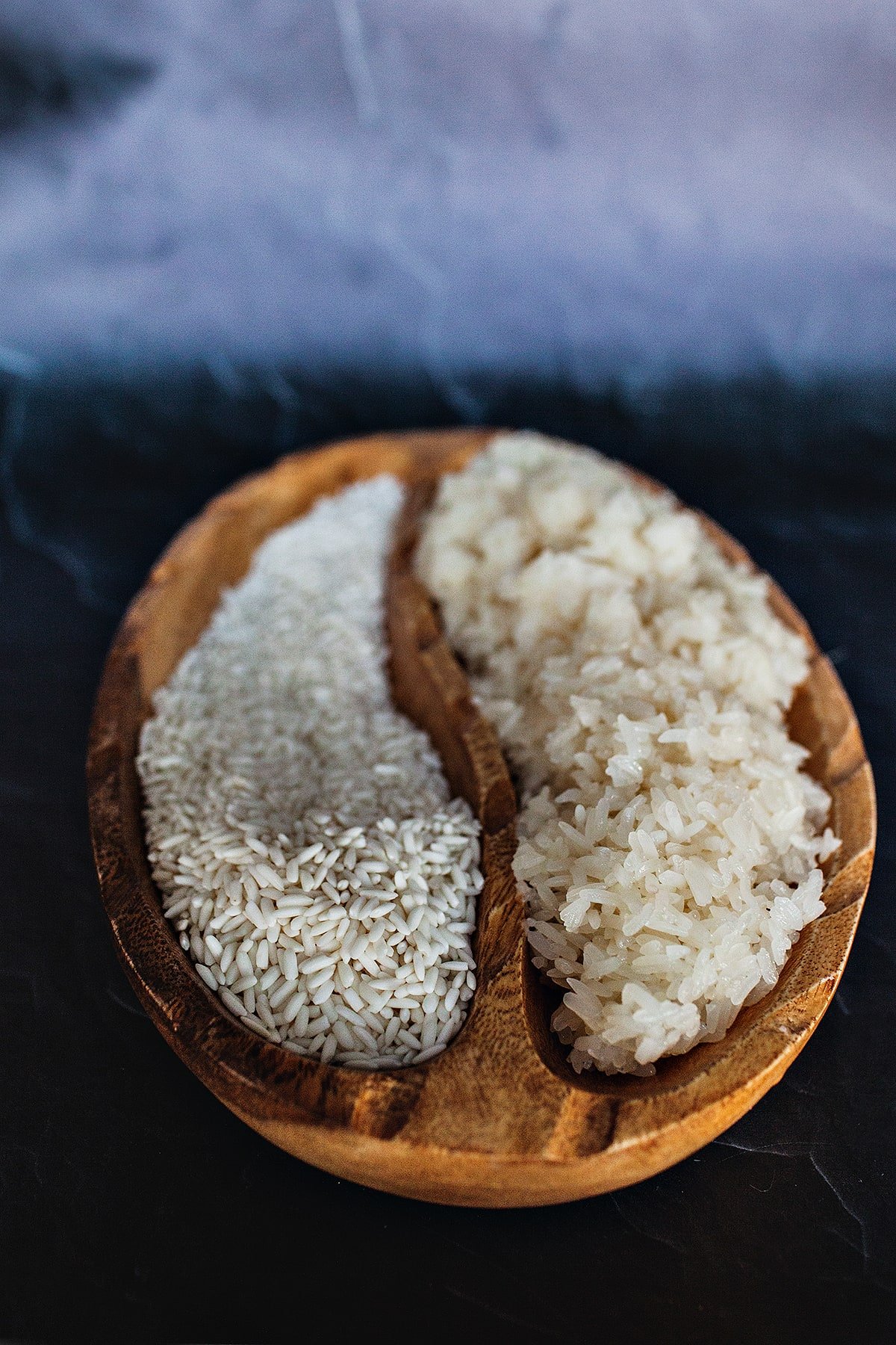 Thai sticky rice in a wooden bowl, one cooked and one uncooked.