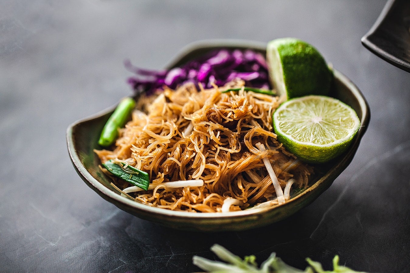 Pad ba mee noodles in a plate with lime garnish