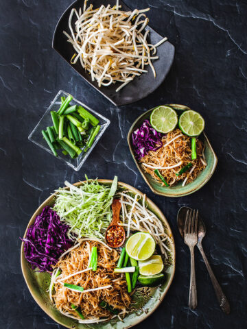 Pad mee on platters with different garnishes.