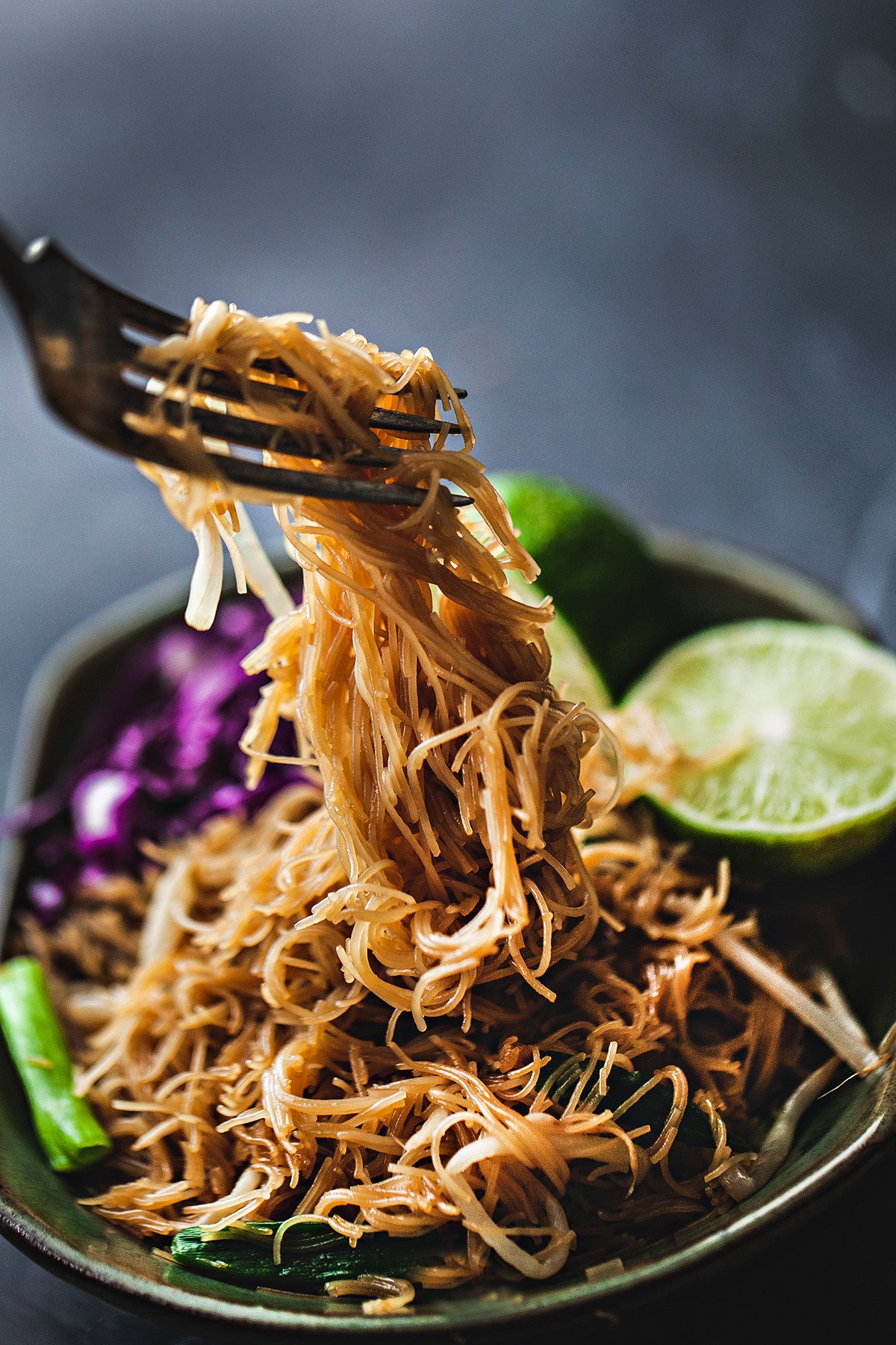 Fork lifting Pad Mee Noodles from a plate.