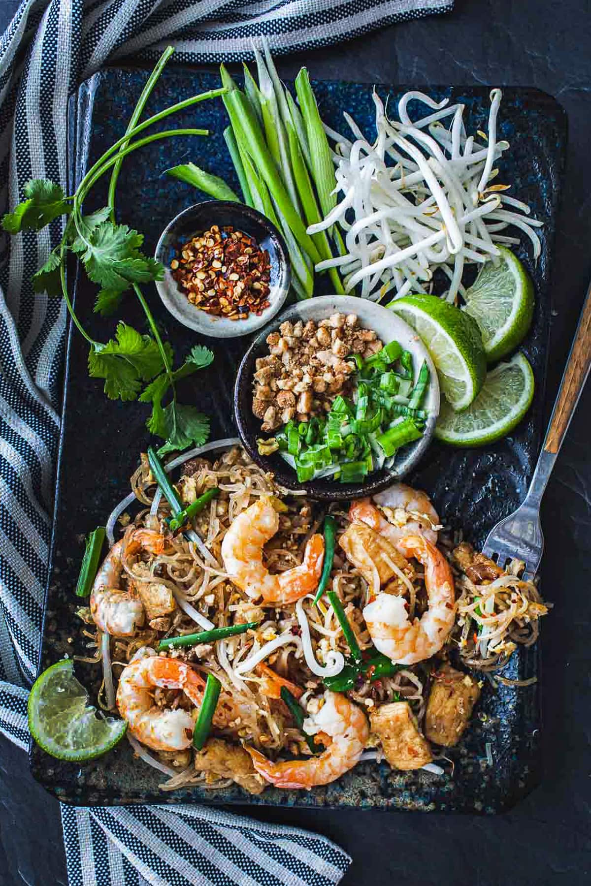 Shrimp pad thai on a platter with garnish