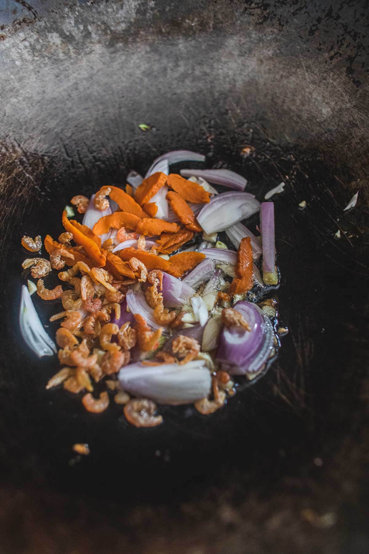 Shrimp, garlic, shallot and preserved radish frying in a wok.