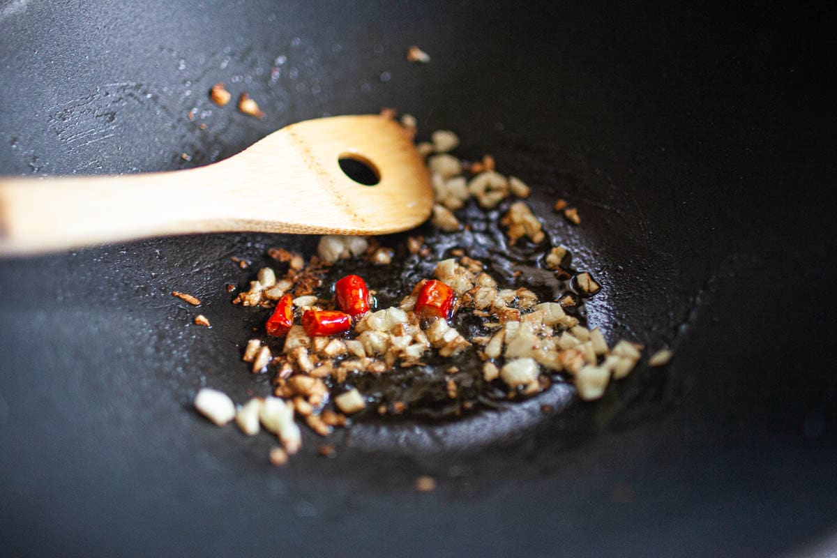 Chili and garlic frying in oil in a wok.