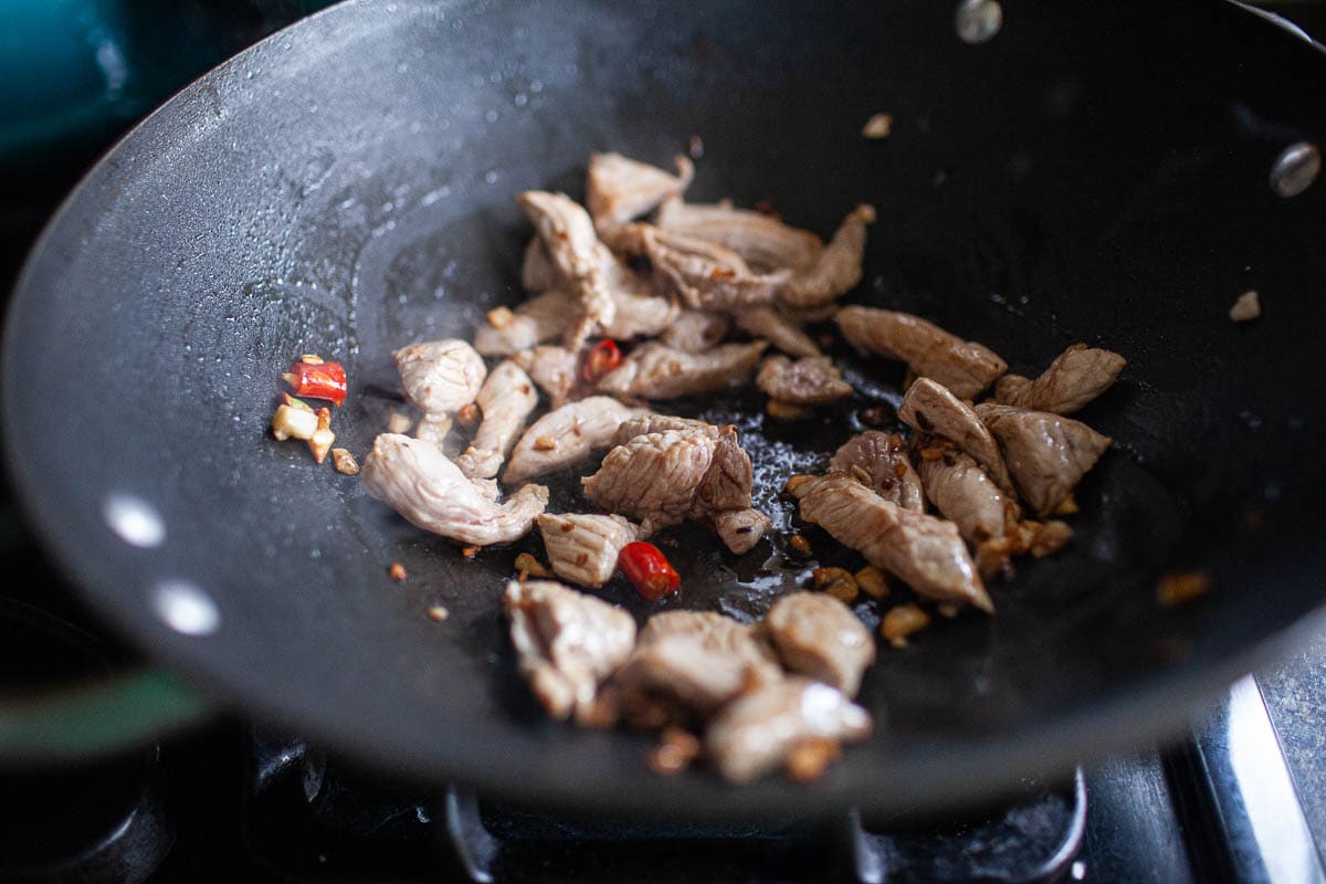 Chicken, garlic, chilis frying in a wok for making drunken noodles. 