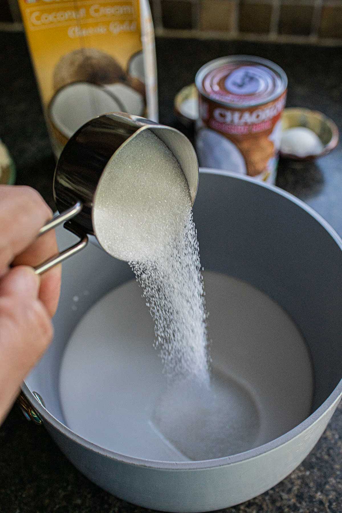 Sugar pouring into a bowl with coconut milk.