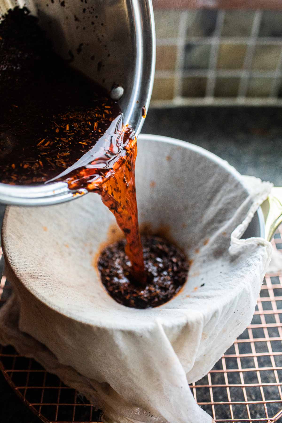 Thai tea drink poured into a cheesecloth in a pot. 