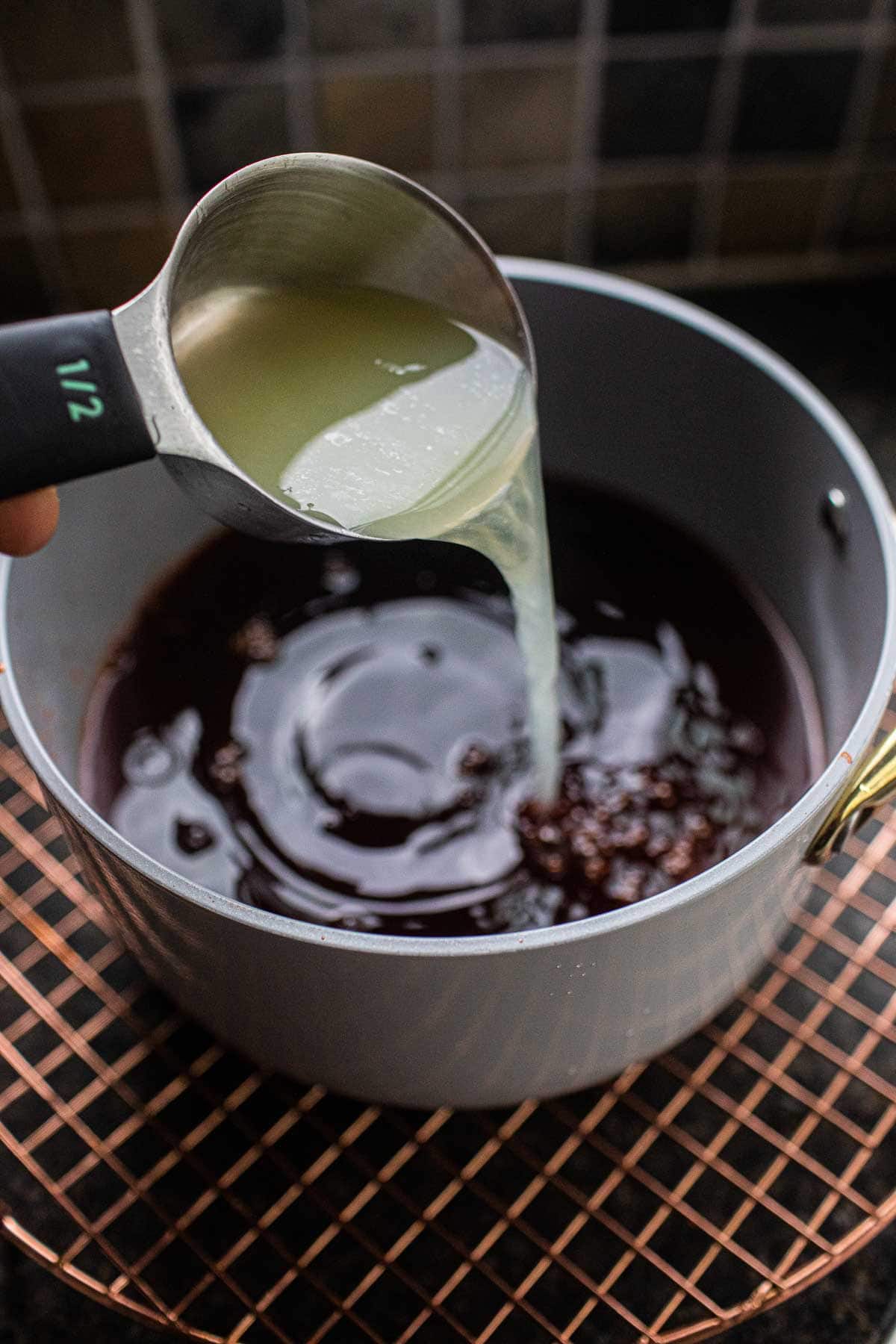 Lime juice poring into the tea mixture in a pot. 