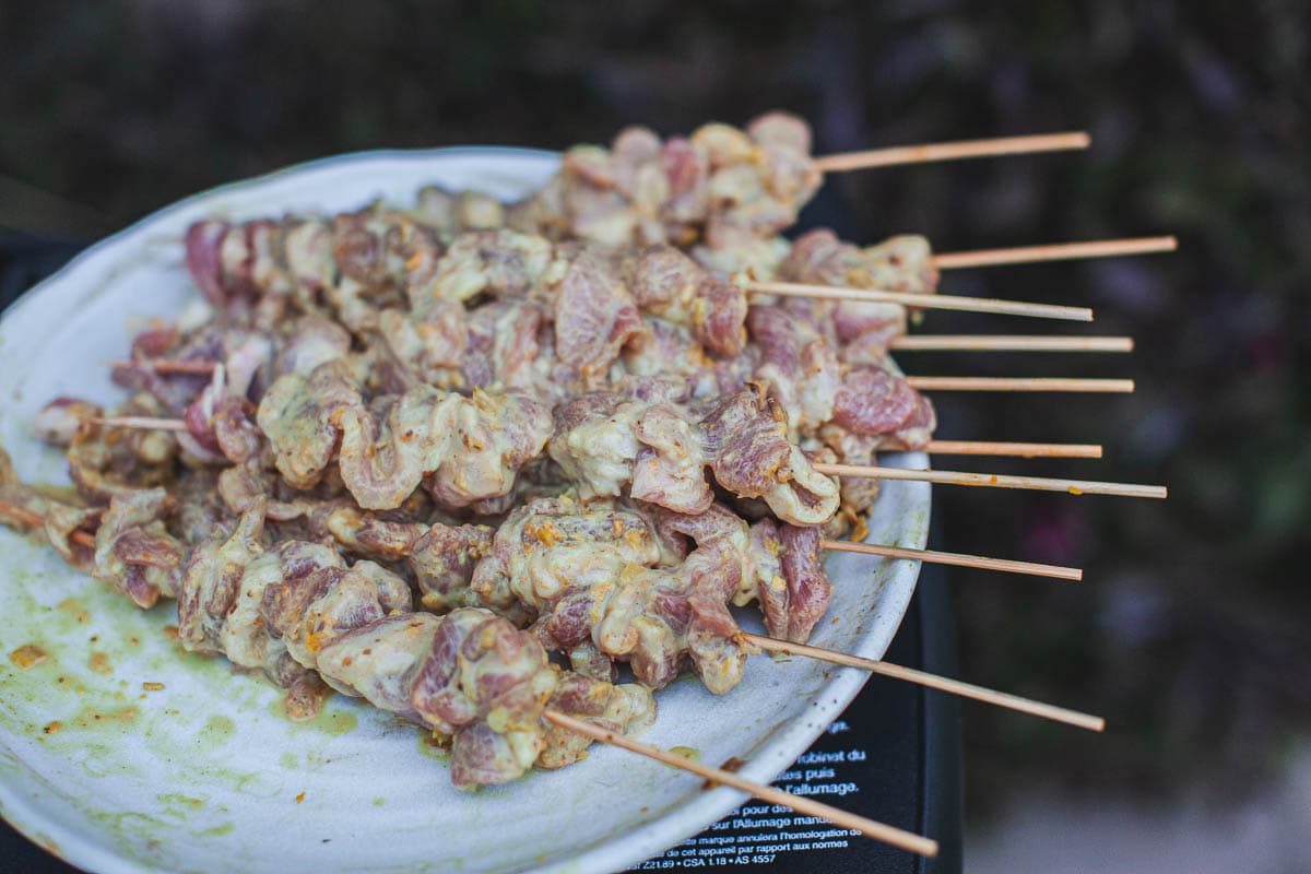  Moo Ping skewers on a white plate. 