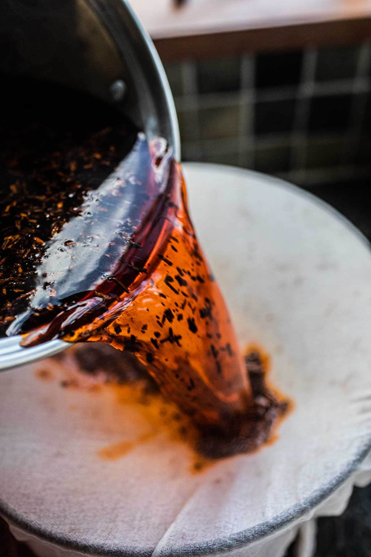 Thai tea straining over cheese cloth into a bowl.