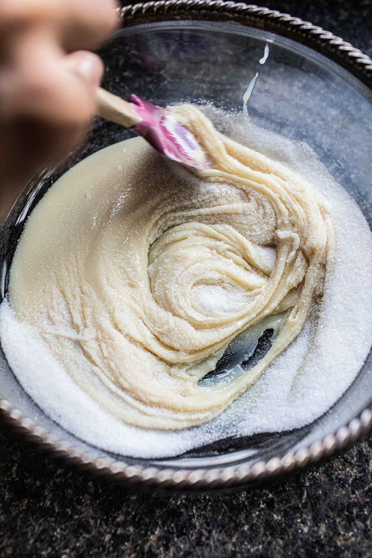 Sweetened condensed milk and sugar in a glass bowl.