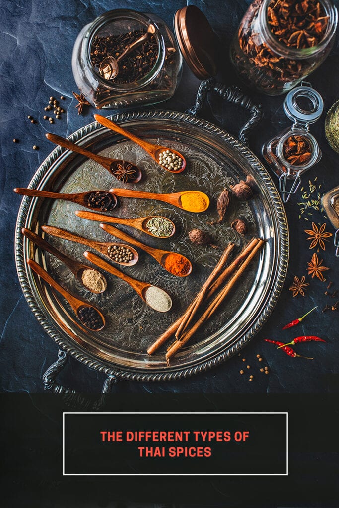 Spices in small spoons on metal tray.