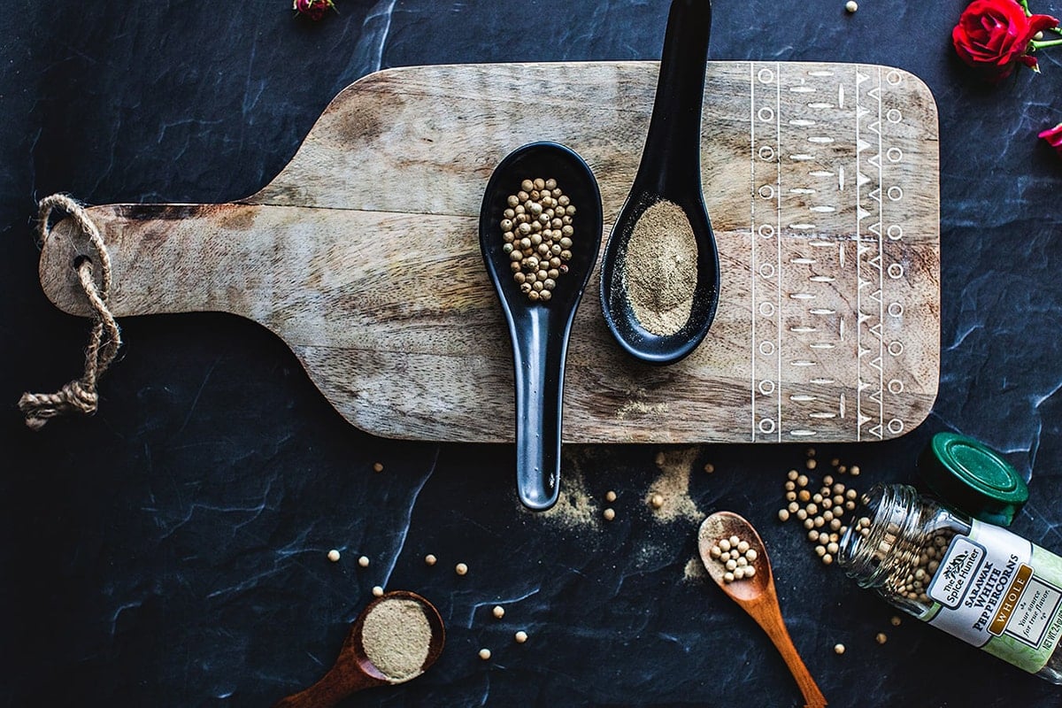 Ground and whole white pepper on a cutting board.