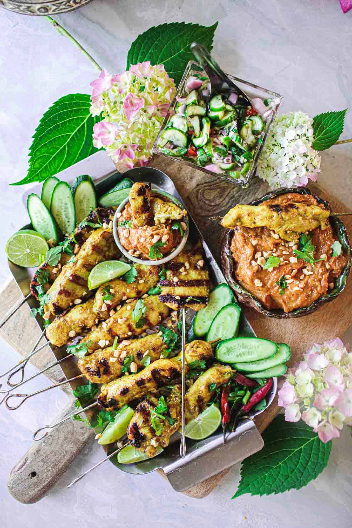 chicken satay skewers on a platter with dipping sauce