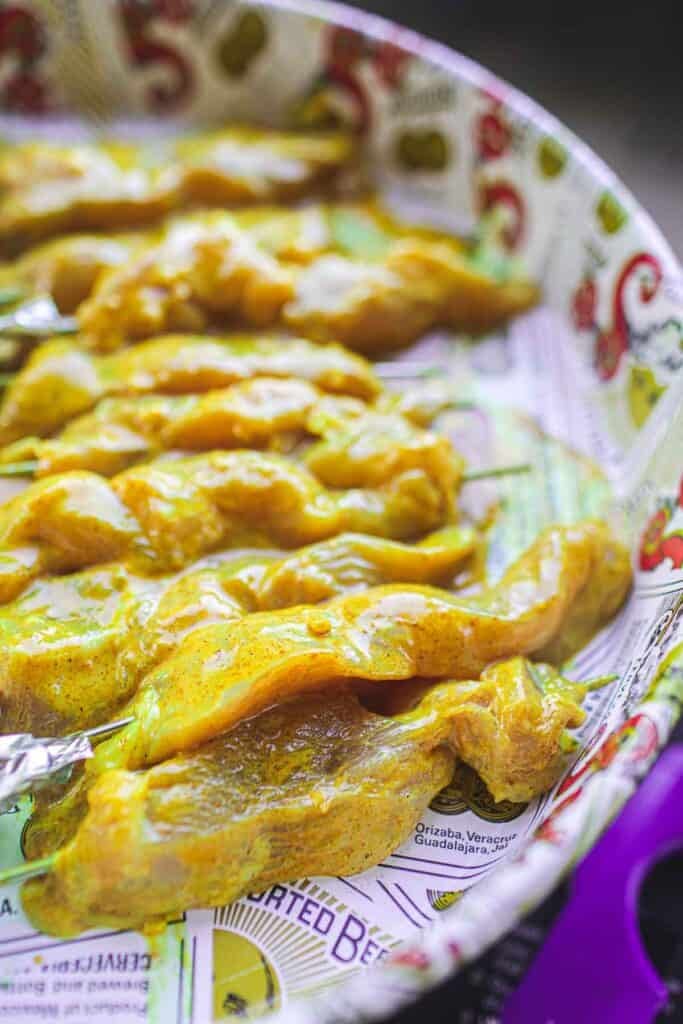 Marinated Thai chicken satay skewers on a platter for grilling.