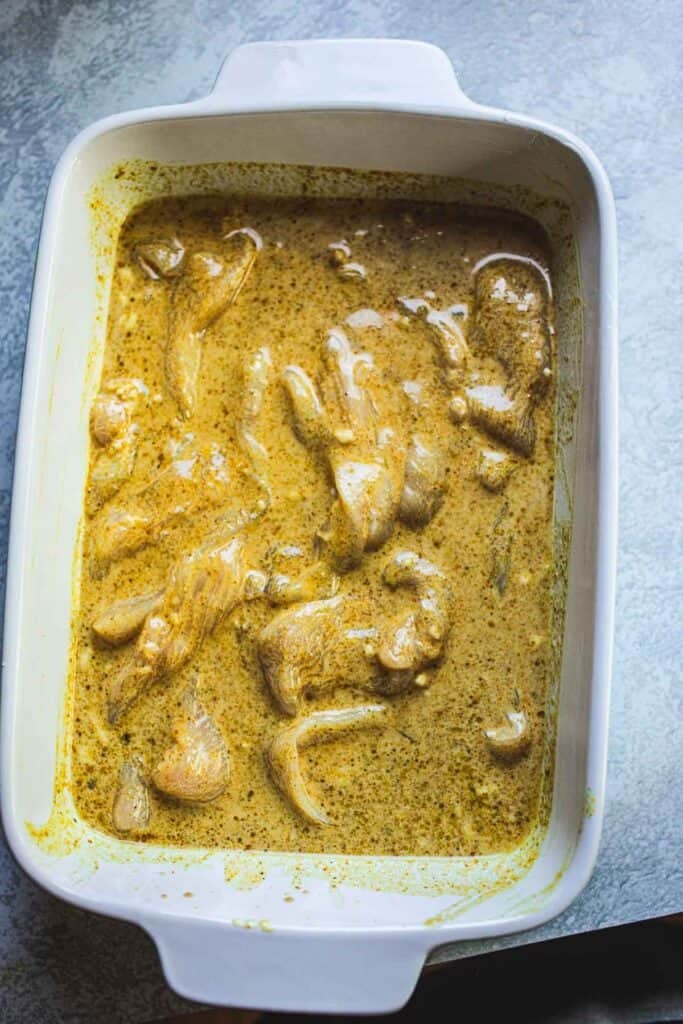 Thai Chicken satay meat marinated in turmeric coconut milk sauce in a pan.