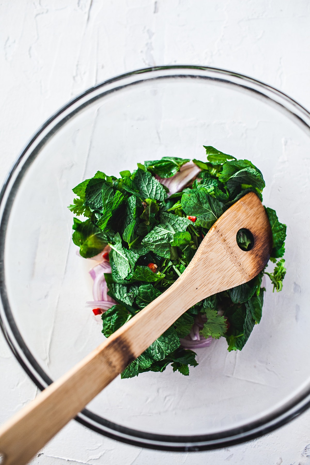 Fresh herbs in a glass bowl for making larb gai salad. 