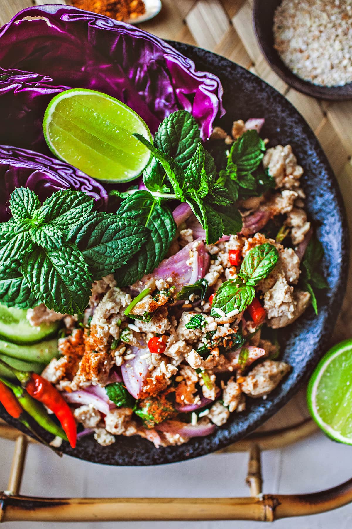 Thai larb gai salad on a platter with herbs garnishes. 