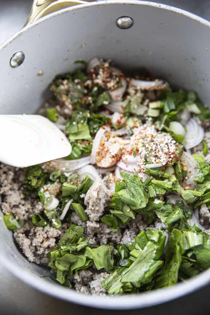 Laab Gai recipe in a pot with ground chicken, herbs and spices.