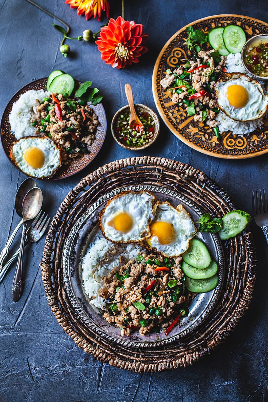 Thai basil chicken Gai Pad Krapao in 3 platters on a table with fried eggs