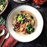 Khao Tom Gai in a bowl with garnishes on the side.