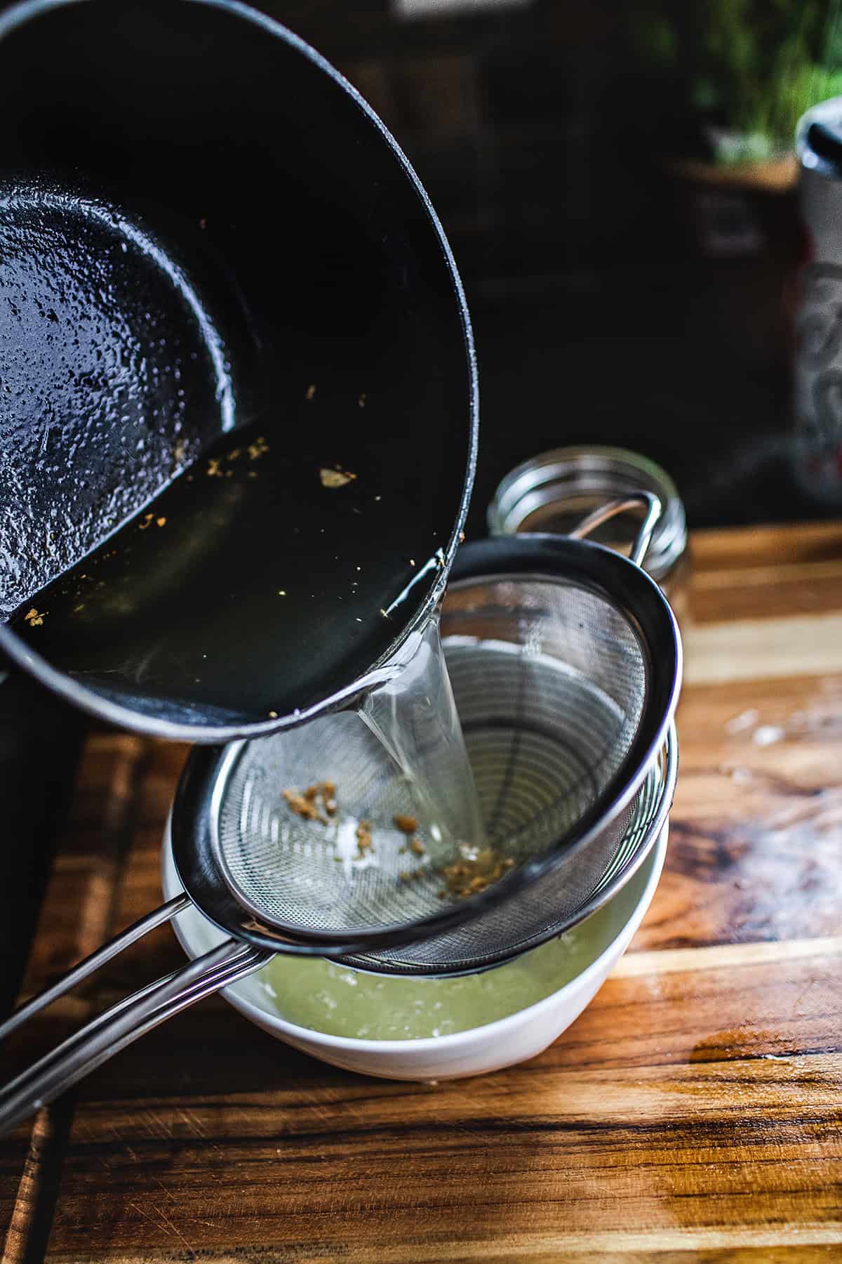 pouring garlic oil into a strainer.