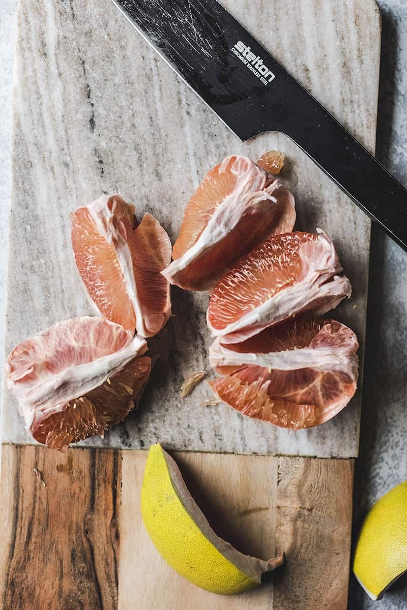 Pomelo cut  in a bowl on a cutting board. 