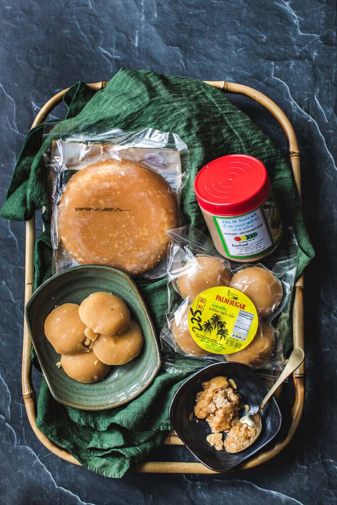 palm sugar in large and small round pugs sitting on a cloth-lined basket.