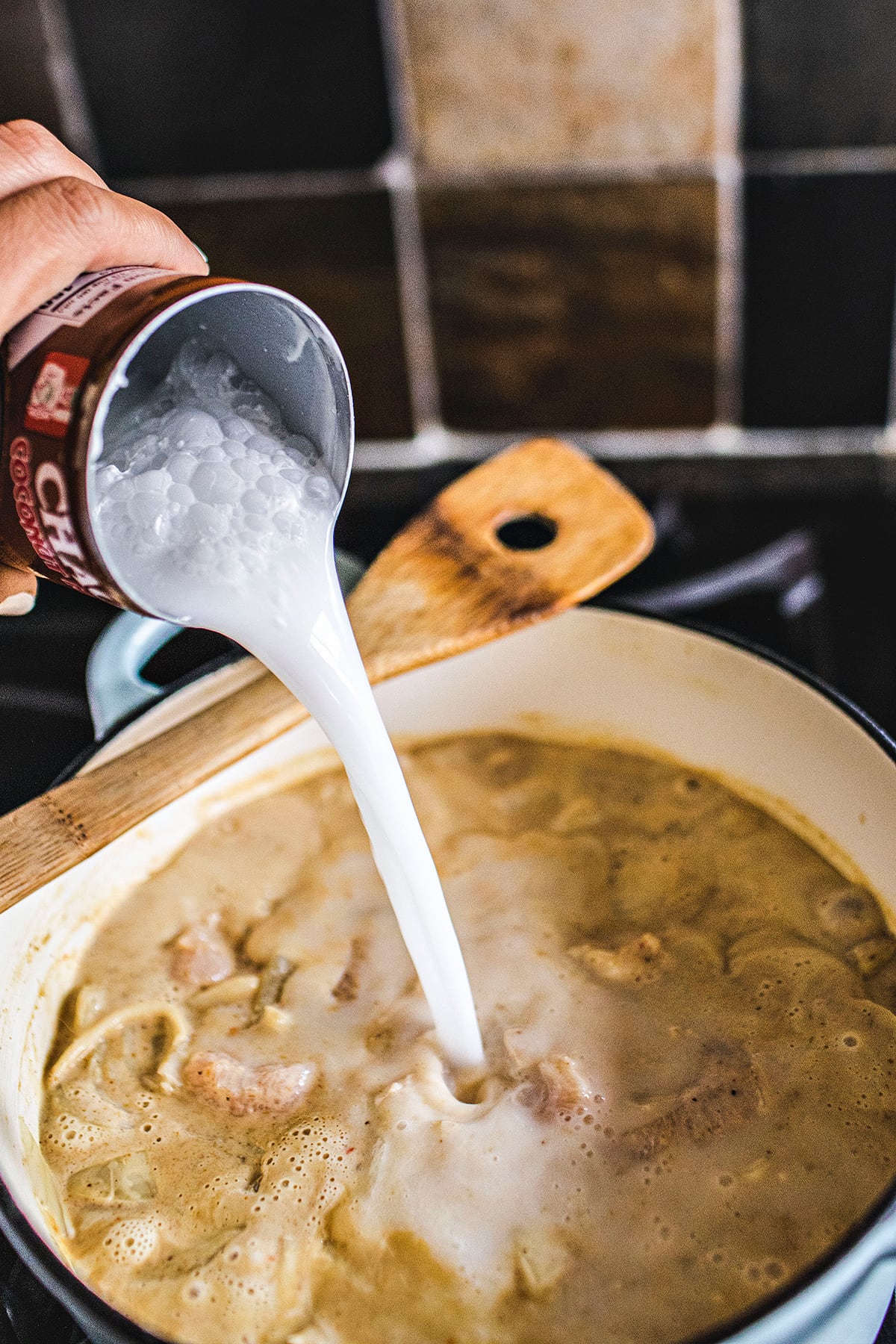 coconut milk pouring into a curry pot