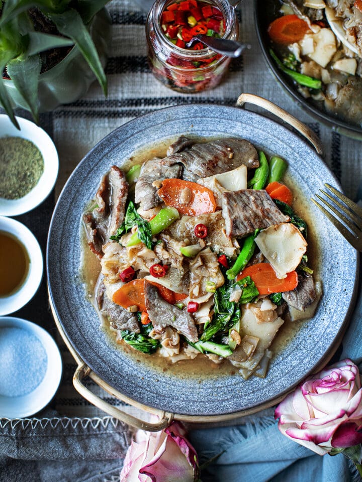 Thai Rad Na with gravy sauce on a blue plate.