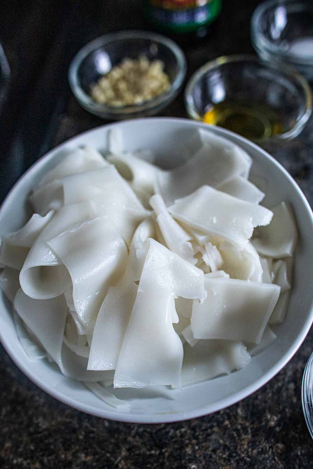 Wide rice noodles for rad na on a plate.