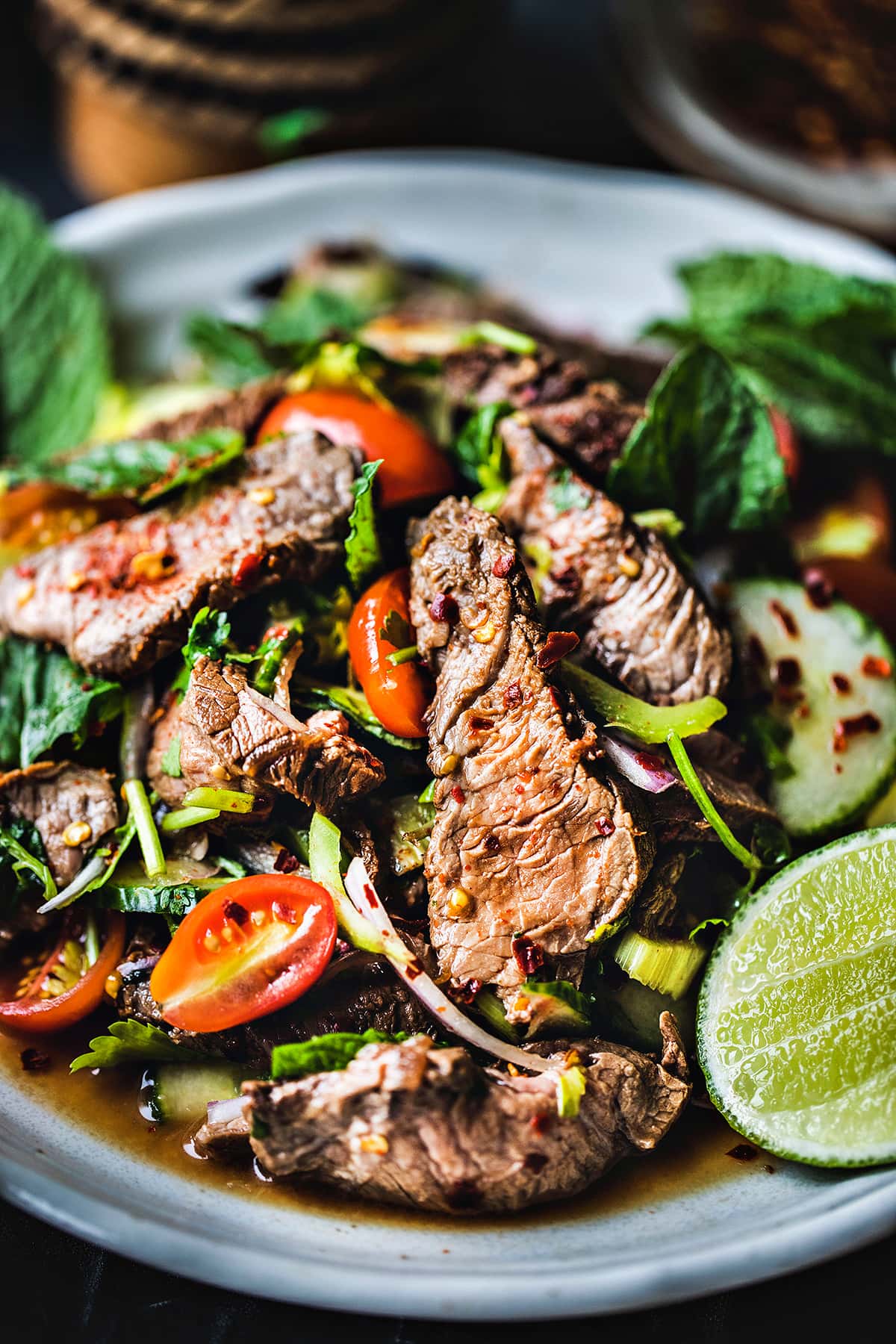 Thai beef salad on a plate with a lime wedge. 