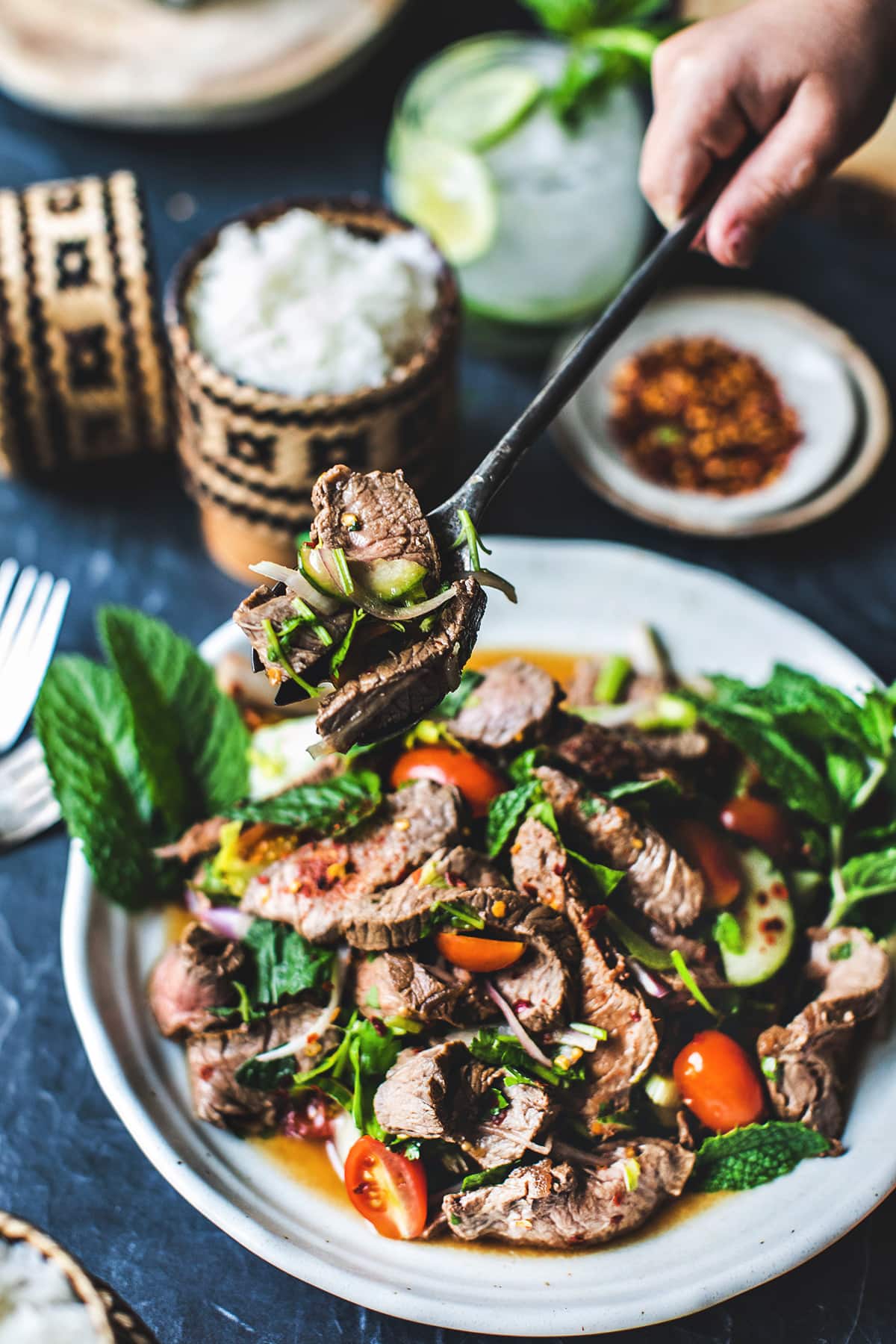 A fork lifting a bite of Thai beef salad.