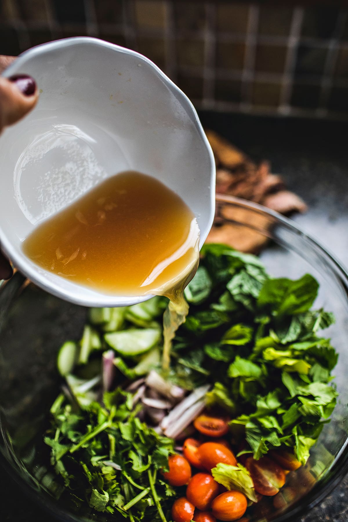 Beef salad dressing pouring into a salad bowl.