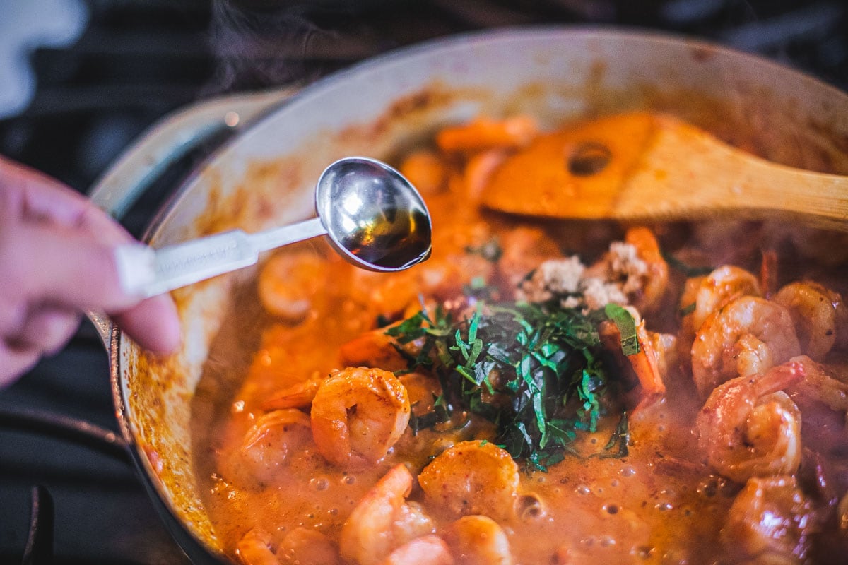 Adding sauce to Prik king curry paste in a pan.