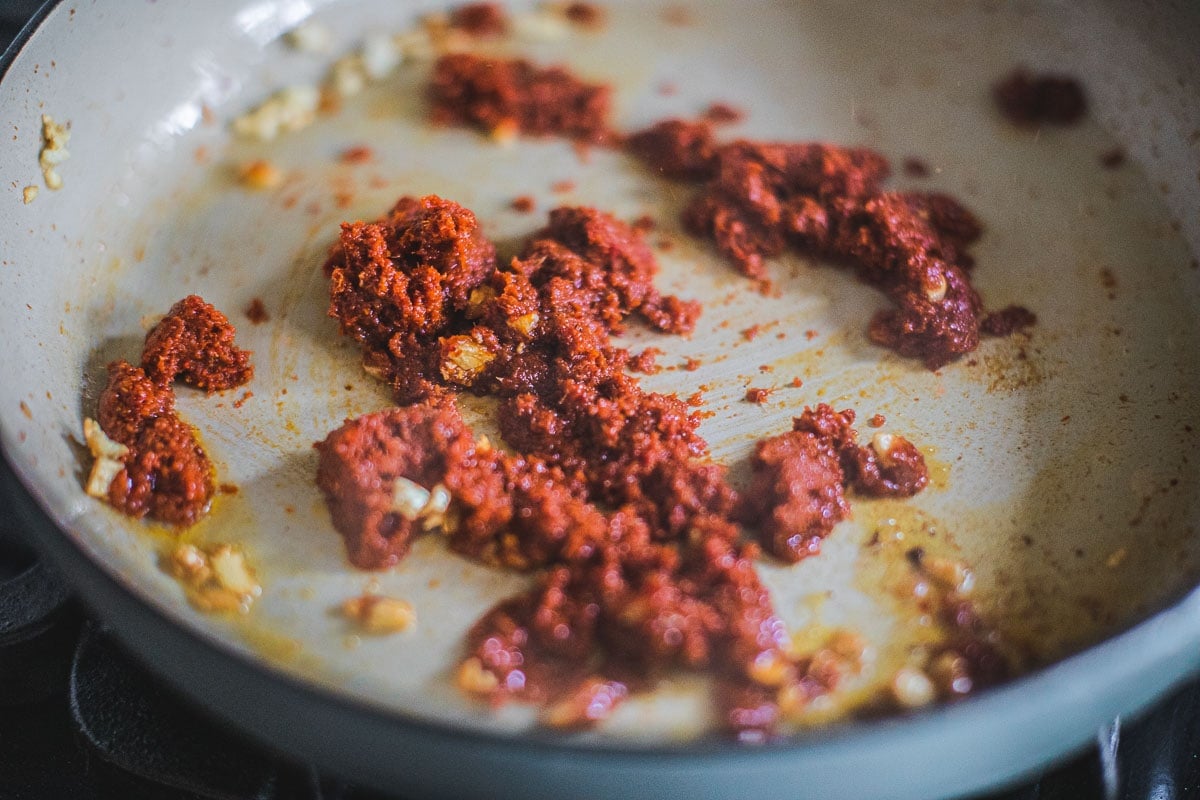 Frying garlic and prik king curry paste in a pan.