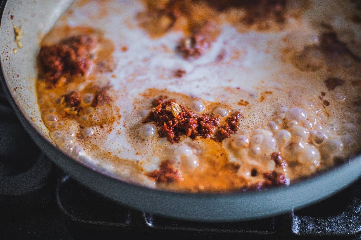 Frying prik king curry paste and coconut milk in a pan.