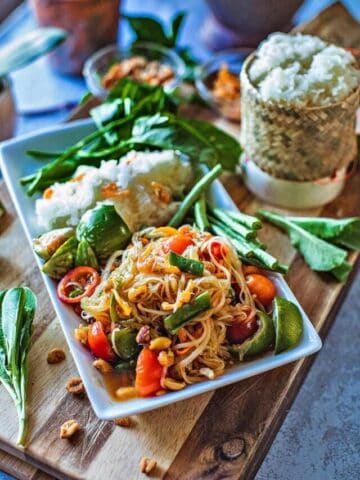 Thai papaya sald on a palte with rice and veggies.