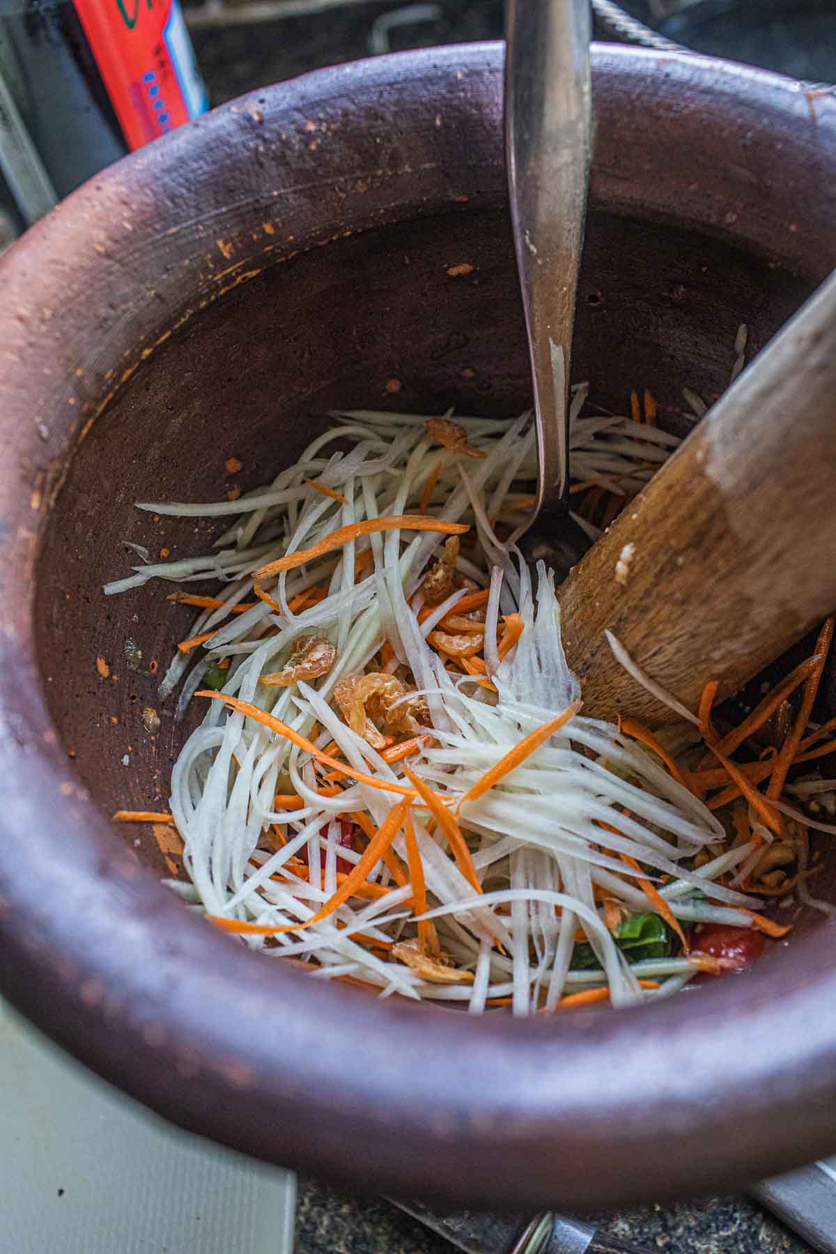 Shredded papaya and carrot in a mortar.