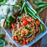 Thai papaya salad in on plate with rice and vegetables on the side.