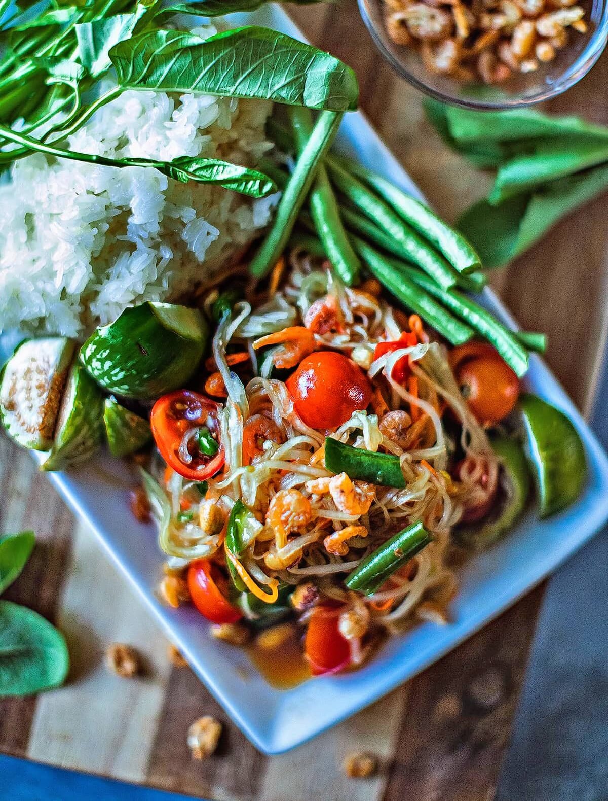 Thai Papaya Salad on a platter with rice and vegetables. 