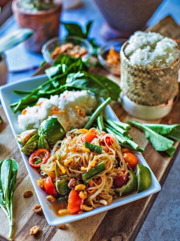 Thai papaya sald on a palte with rice and veggies.