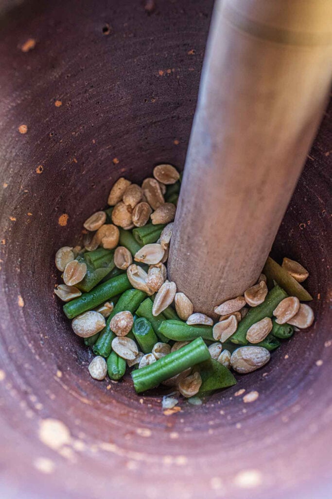 Peanuts and beans in a mortar and pestle inside.
