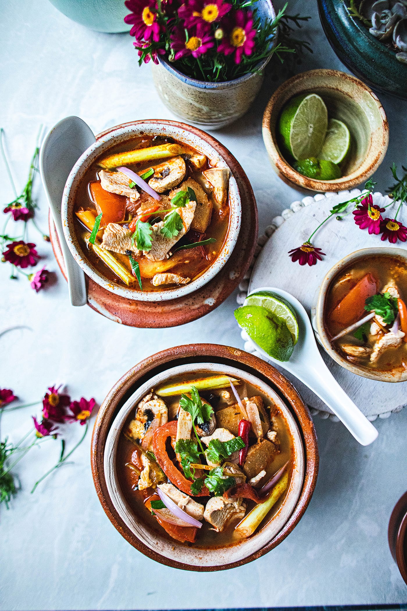 tom yum soup in 2 small bowls on the table with spoons