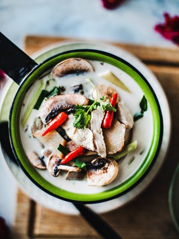Tom Kha gai is a very well known Thai soup made by using chicken, coconut milk, herbs fish sauce, and lime juice. It is a creamy light soup that is not only delicious but also full of fresh herbs that will keep you healthy all winter long.  #thaicoconutsoup #thaichickencoconutsoup #tomkhagai #thaicoconutchickensoup #easythaisoup