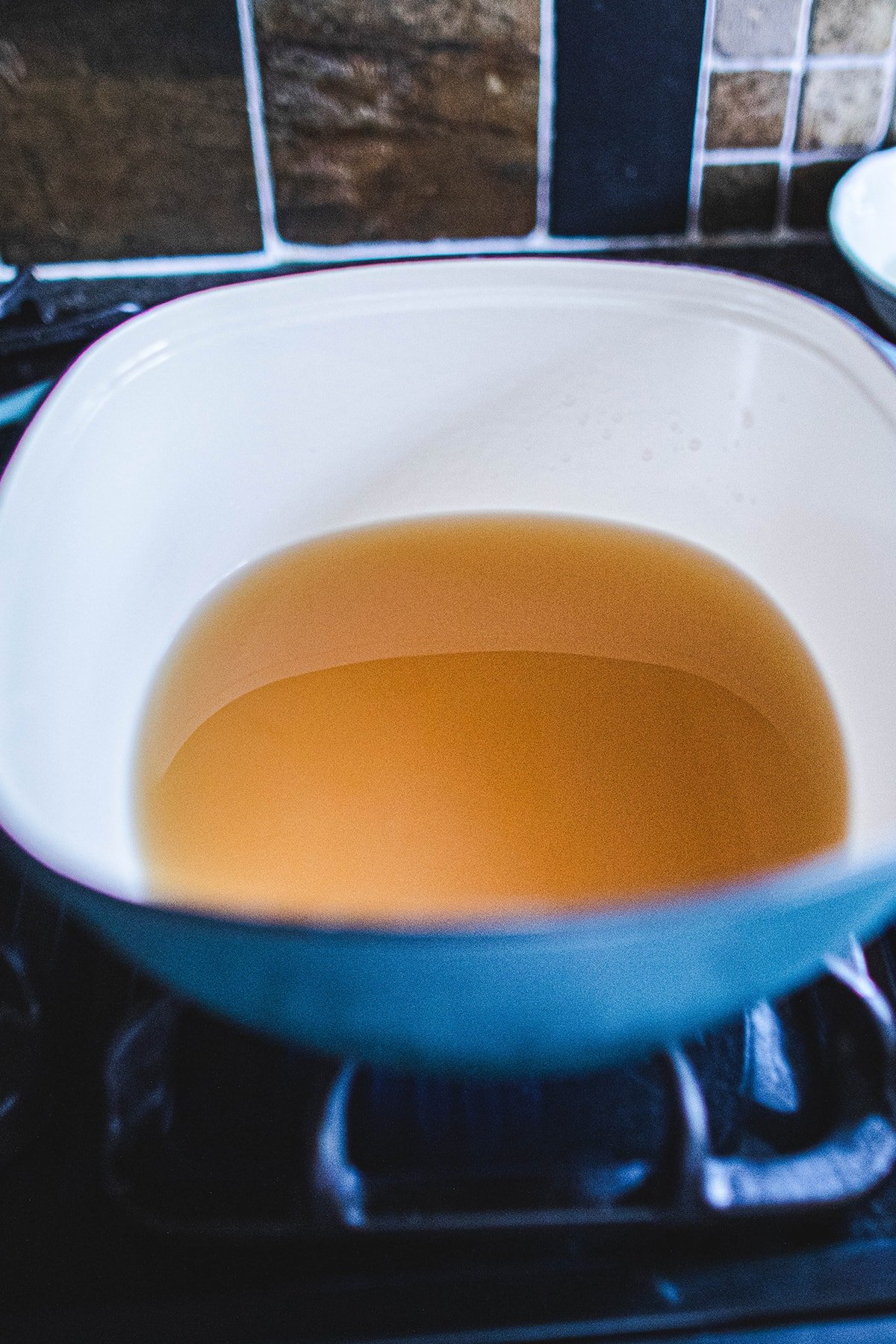 tom yum clear broth in a blue soup pot